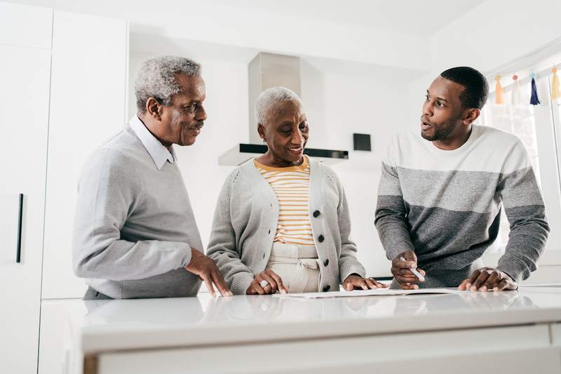 Older couple speaks with agent in kitchen of a home for sale.