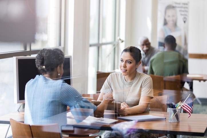 Loan officer meets with woman at bank office to discuss her mortgage APR