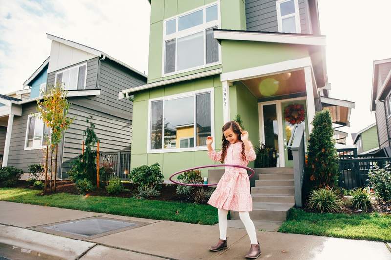 Child playing with a hula hoop in a neighborhood with a homeowners association.