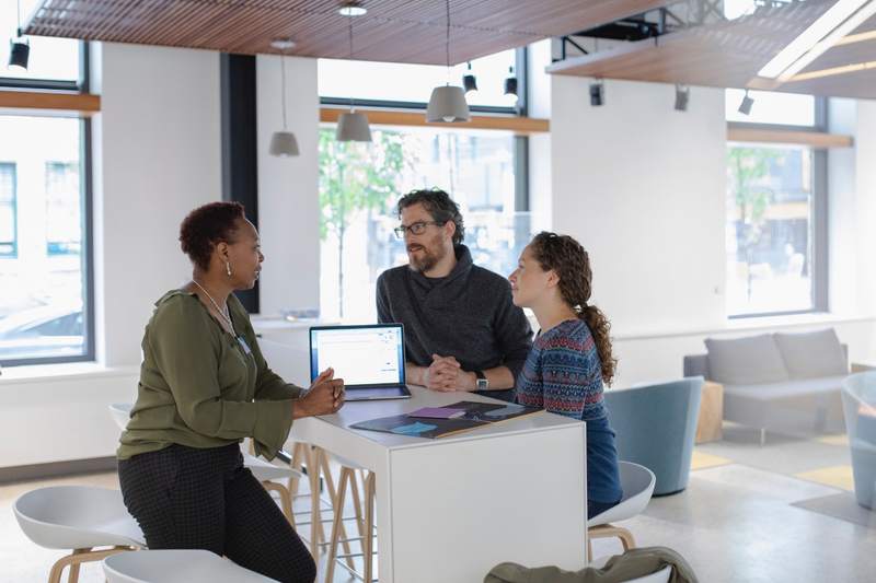 Couple looking to refinance their mortgage talk with a lender.