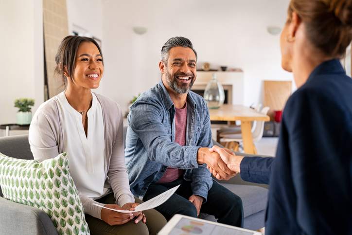 A couple shaking hands with a financial planner.