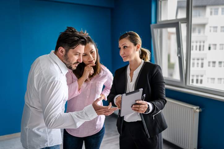 Real estate agent and young couple making deals for property.