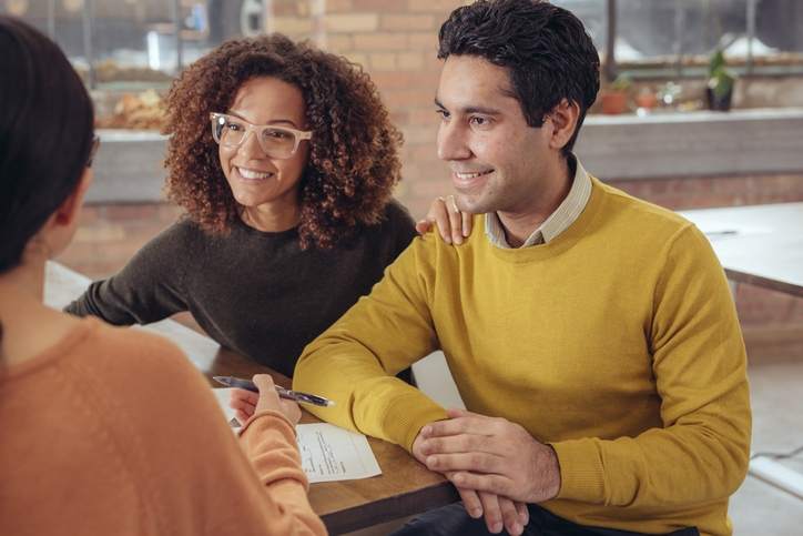 Couple smile while meeting with a loan agent.