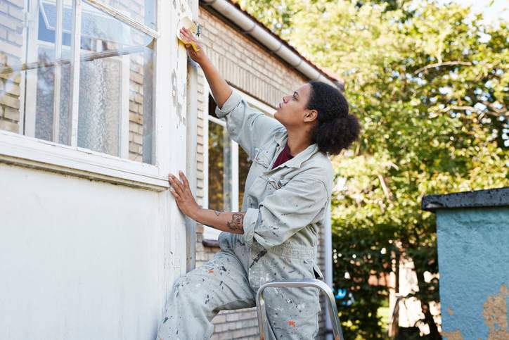 Person fixing house exterior paint to improve home appraisal.