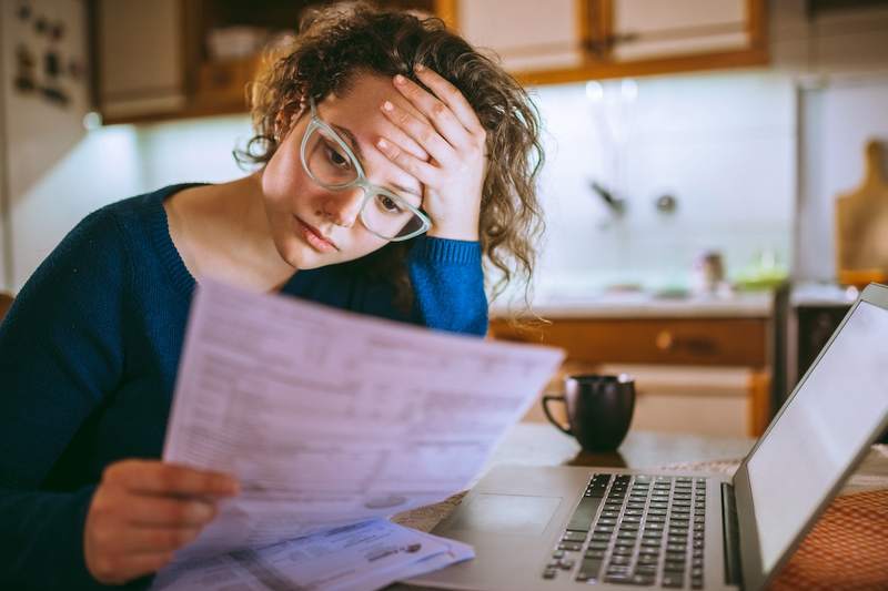 Stressed woman reviews financial papers for mortgage loan modification.