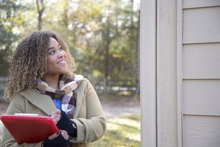 A woman appraises the exterior of a home.